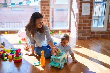 Güzel öğretmen ve bebek anaokulunda bir sürü oyuncakla oynuyorlar.