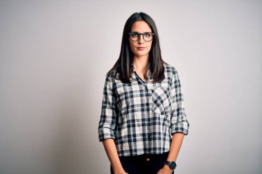 Mavi gözlü, beyaz arka planda günlük gömlek ve gözlük takan esmer bir kadın. Yüzünde ciddi bir ifadeyle rahatlamış. Basit ve doğal bir şekilde kameraya bakıyorsun..