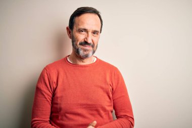 Middle age hoary man wearing casual orange sweater standing over isolated white background with hands together and crossed fingers smiling relaxed and cheerful. Success and optimistic