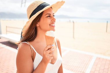 Yazın güneşli bir gününde kumsalda dondurma yiyen güzel bir kadın.