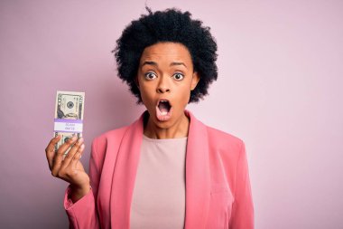 Kıvırcık saçlı, elinde dolar banknotları olan Afro-Amerikalı genç bir iş kadını. Şaşırmış bir yüzle korkmuş ve korku ifadesinden heyecanlanmış.