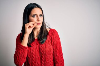 Mavi gözlü genç esmer kadın izole edilmiş beyaz arka plan ağzının üzerine gündelik süveter giyiyor ve dudakları parmaklarıyla fermuar gibi kapalı. Gizli ve sessiz, tabu konuşması