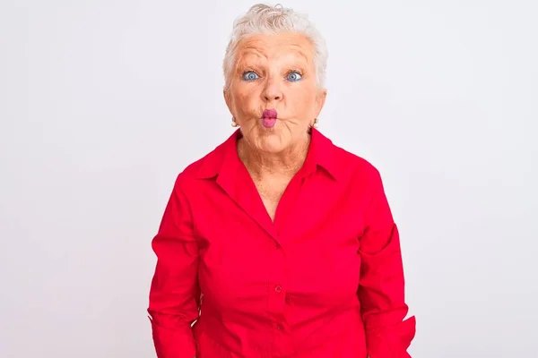 高个子灰发女人穿着红色休闲装 站在孤立的白色背景之上 用嘴唇 疯狂和滑稽的姿势做鱼脸 有趣的表达方式 — 图库照片