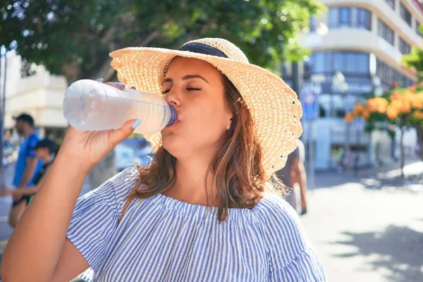 夏の晴れた日に新鮮な水を飲んで街の通りを歩く幸せな笑顔の若い美しい女性 — ストック写真