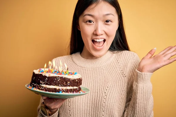 Junge Asiatin Hält Geburtstagstorte Mit Brennenden Kerzen Auf Gelbem Hintergrund — Stockfoto