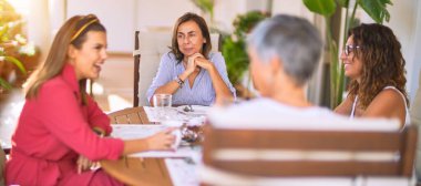 Genç ve güzel bir kız mutlu ve kendinden emin bir şekilde terasta oturmuş bir fincan kahve içiyor.