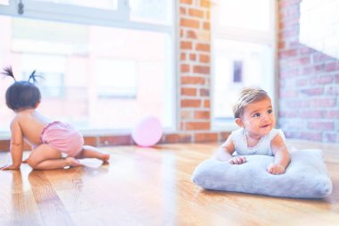 Güzel bebek mutlu kızlar, evde anaokulunda birlikte oynuyorlar, tahta zeminde oturuyorlar.