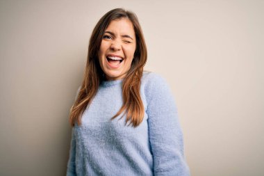 Kış süveteri giymiş güzel bir kadın izole bir arka planın başında durmuş kameraya seksi bir ifadeyle bakıyor, neşeli ve mutlu bir yüzle..