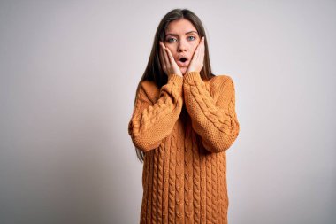 Mavi gözlü genç bir kadın beyaz arka planda dikilen sıradan bir süveter giyiyor. Korkmuş ve şokta. Şaşırmış ve şaşırmış bir halde.