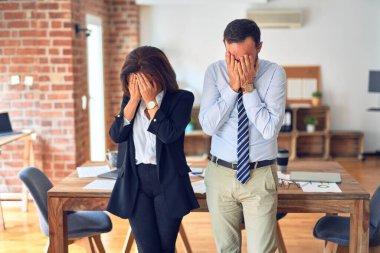 Ofisteki bir toplantıda birlikte çalışan iki orta yaşlı iş adamı, ağlarken yüzünü ellerle kapatan üzgün bir ifadeyle. Depresyon kavramı.