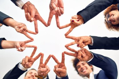 Bir grup iş adamı mutlu ve kendinden emin gülümsüyor. Yüzünde gülümsemeyle bir çemberin üzerinde durup ofiste parmaklarıyla sembol çiziyor..