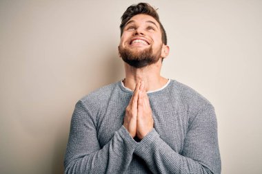 Sakallı, mavi gözlü, genç, yakışıklı bir adam. Sıradan bir süveter giyiyor. Elleri bağlı yalvarıyor ve dua ediyor. Yalvarıyorum..