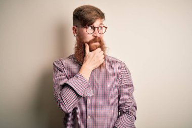 Güzel İrlandalı kızıl saçlı, sakallı, soyutlanmış arka planda gözlüklü, eli çenesinde soru soran, düşünceli bir iş adamı. Düşünceli bir yüzle gülümsüyor. Şüphe kavramı.