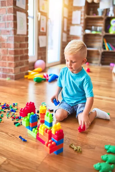年轻的高加索小孩在幼儿园玩玩具块 学龄前男孩很高兴在游戏室建了一座塔 — 图库照片