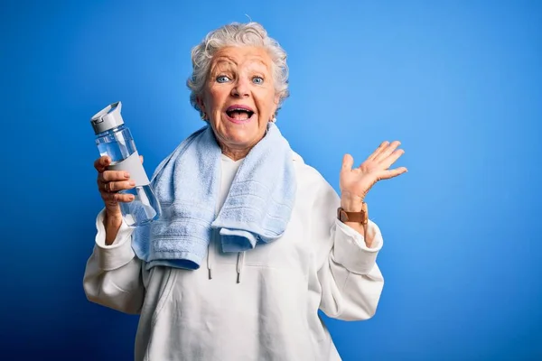 Senior Beautiful Sporty Woman Holding Bottle Water Standing Isolated Blue — Stock Photo, Image