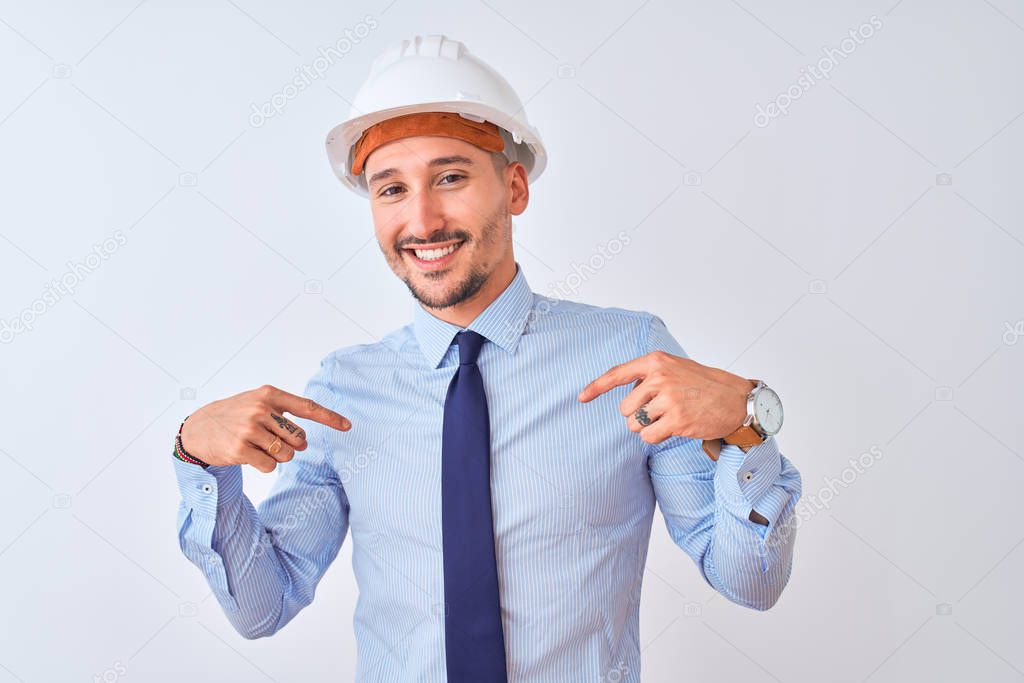 Young business man wearing contractor safety helmet over isolated background looking confident with smile on face, pointing oneself with fingers proud and happy.