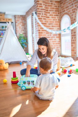 Güzel öğretmen ve bebek anaokulunda bir sürü oyuncakla oynuyorlar.