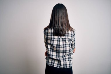 Mavi gözlü, beyaz arka planda günlük gömlek ve gözlük takan esmer bir kadın. Kollarını kavuşturup arkaya bakıyor.