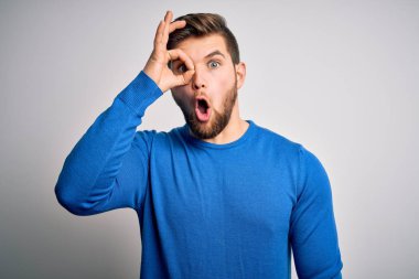 Sakallı, mavi gözlü, sıradan bir süveter giyen, şaşırmış yüzüyle, parmaklarından bakan genç, yakışıklı sarışın bir adam. İnançsız ifade.