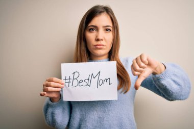 Elinde en iyi anne mesajı olan genç ve güzel bir kadın. Anneler gününü kızgın bir suratla kutluyor. Negatif işaretler baş parmakları aşağıda.