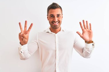 Soyutlanmış arka planda zarif gömlekler giyen genç yakışıklı iş adamı sekiz numaralı parmaklarını gösterip işaret ederken kendinden emin ve mutlu gülümsüyor..
