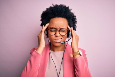 Genç Afrikalı Amerikalı çağrı merkezi operatörü, kıvırcık saçlı, kulaklık kullanan, baş ağrısı çeken, çaresiz ve stresli bir kadın. Çünkü ağrı ve migren. Ellerini başının üstüne koy..