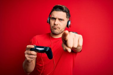 Mavi gözlü genç oyuncu oyun oynuyor. Oyun sahası joystick 'i kullanarak kamerayı işaret ediyor. Ve sen, el işareti, ön taraftan pozitif ve kendinden emin bir hareket.