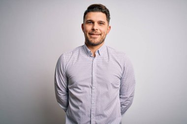 Mavi gözlü genç iş adamı mutlu ve havalı bir gülümsemeyle izole bir arka planda duruyor. Şanslı kişi..