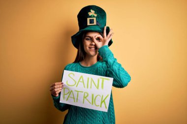 Yeşil şapkalı bir kadın Aziz Patrick Günü 'nü kutluyor. Elinde Aziz Patrick' in mutlu yüzüyle bir pankart var. Tamam.