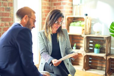 Mutlu ve kendinden emin gülümseyen iki orta yaşlı iş adamı. Ofisteki belgeleri okurken gülümseme ile birlikte çalışmak.