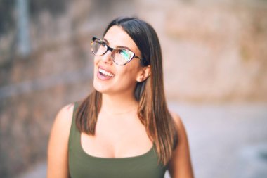 Mutlu ve kendinden emin gülümseyen genç ve güzel bir kadın. Kasaba caddesinde yüzünde gülümsemeyle dikilirken