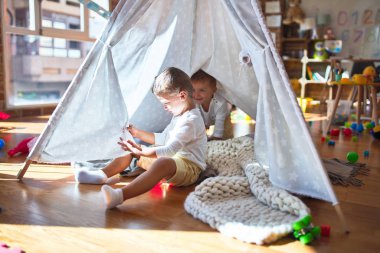 Anaokulunda bir sürü oyuncağın etrafında oynayan sevimli sarışın ikizler.