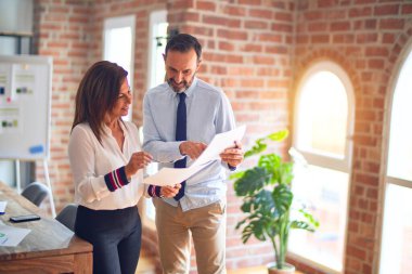 Mutlu ve kendinden emin gülümseyen iki orta yaşlı iş adamı. Yüzünde gülümsemeyle büroda belgeleri tutarak birlikte çalışıyoruz.