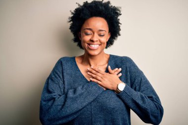 Kıvırcık saçlı, elleri göğsünde, gözleri kapalı gülümseyen ve yüzünde minnet ifadesi olan güzel Afro-Amerikan bir kadın. Sağlık kavramı.