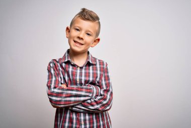 Mavi gözlü, zarif gömlekli, izole edilmiş arka planda duran, kollarını kavuşturup kameraya gülümseyen küçük beyaz bir çocuk. Pozitif kişi.