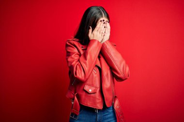 Genç, güzel, esmer bir kadın. Günlük ceket giyiyor. Kırmızı arka planda duruyor. Depresyon kavramı.