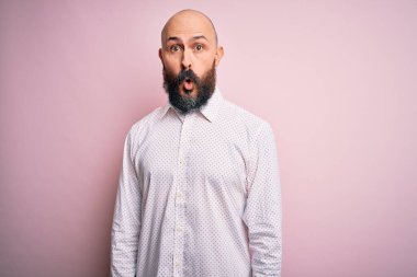 Sakallı, zarif, pembe gömlekli yakışıklı bir adam. Pembe arka planda korkmuş ve şok olmuş..