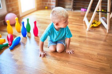 Anaokulunda bowling oynayan beyaz bir çocuk. Anaokulu çocuğu oyuncaklarla oyun odasında mutlu.