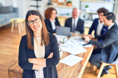 Bir grup iş adamı bir toplantıda birlikte çalışırken mutlu ve kendinden emin gülümsüyor. Bir tanesi, yüzünde gülümsemeyle büroya bakıyor..