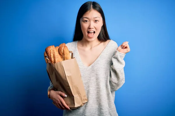 Genç Asyalı Bir Kadın Mavi Izole Arka Planda Ekmek Poşeti — Stok fotoğraf