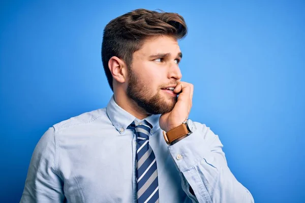 ひげと青い目をした若いブロンドのビジネスマンは エレガントなシャツを着て 口の中に爪をかむ上で手でストレスと緊張を見て立ってネクタイ 不安の問題 — ストック写真