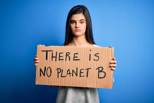 Young beautiful brunette activist woman holding banner protesting to care the planet with a confident expression on smart face thinking serious