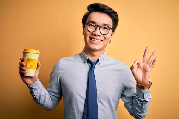 Молодий Вродливий Китайський Чоловік Склянку Кави Жовтому Фоні Тримаючи Знак — стокове фото