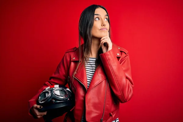 若い美しいブルネットのオートバイのヘルメットと質問について考える赤いジャケット深刻な顔を持つオートバイの女性は 非常に混乱したアイデア — ストック写真