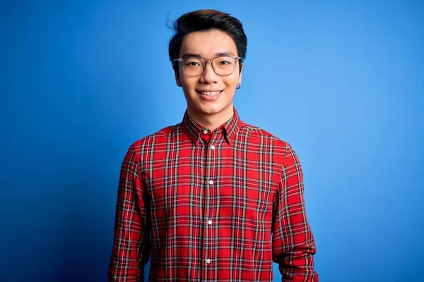 幸せとクールな笑顔で青の背景にカジュアルなシャツと眼鏡を身に着けている若いハンサムな中国人男性 運のいい人 — ストック写真