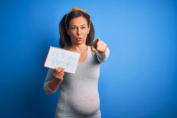 中年妊娠中の女の子を期待しています赤ちゃん男の子上の青の背景を指しています指でカメラとあなたに 手のサイン 正と自信を持ってジェスチャーからフロント — ストック写真
