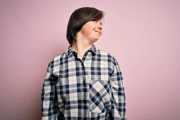 若いダウン症候群の女性の顔に笑顔で横に離れて見てピンクの背景にカジュアルなシャツを着て 自然な表情 自信を持って — ストック写真