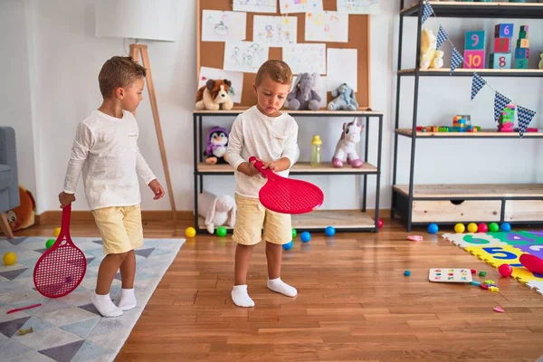 Adorable blonde twins playing around lots of toys at kindergarten