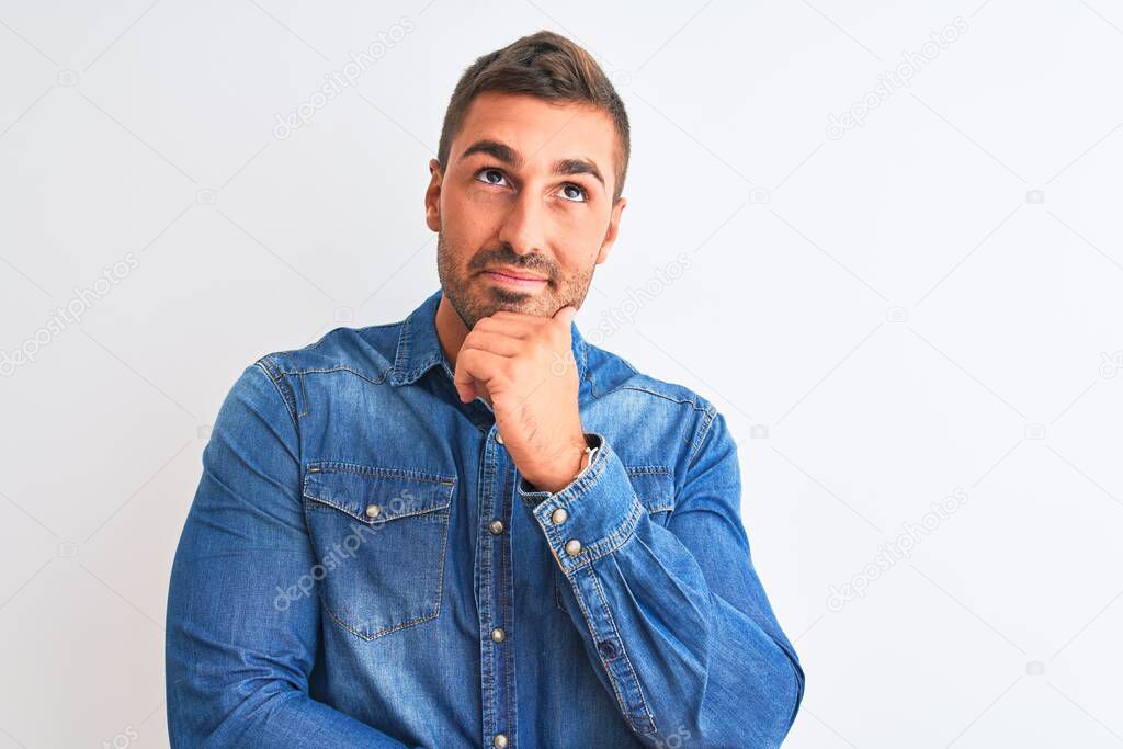 Young handsome man wearing denim jacket standing over isolated background with hand on chin thinking about question, pensive expression. Smiling with thoughtful face. Doubt concept.
