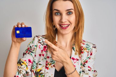 Kafkasyalı iş kadını kredi kartını soyutlanmış arka planda tutuyor. Elle ve parmakla işaret ederek çok mutlu.